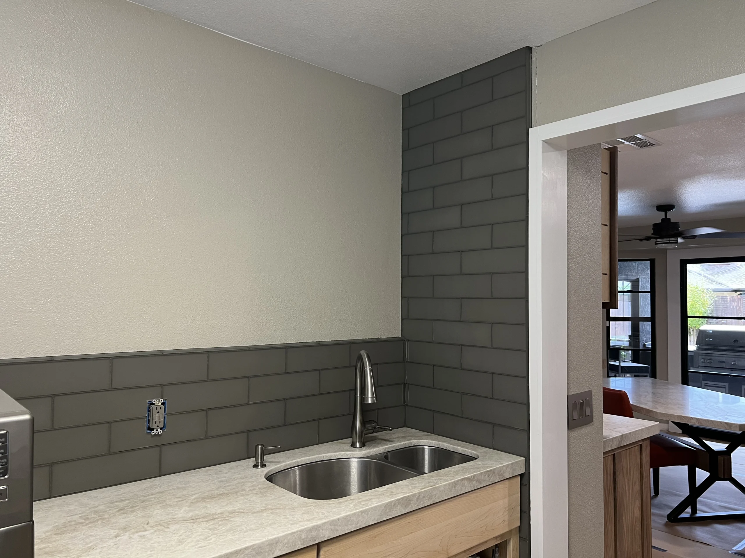 Gray subway tile backsplash installation in a Fresno kitchen with a stainless steel sink and light countertops.