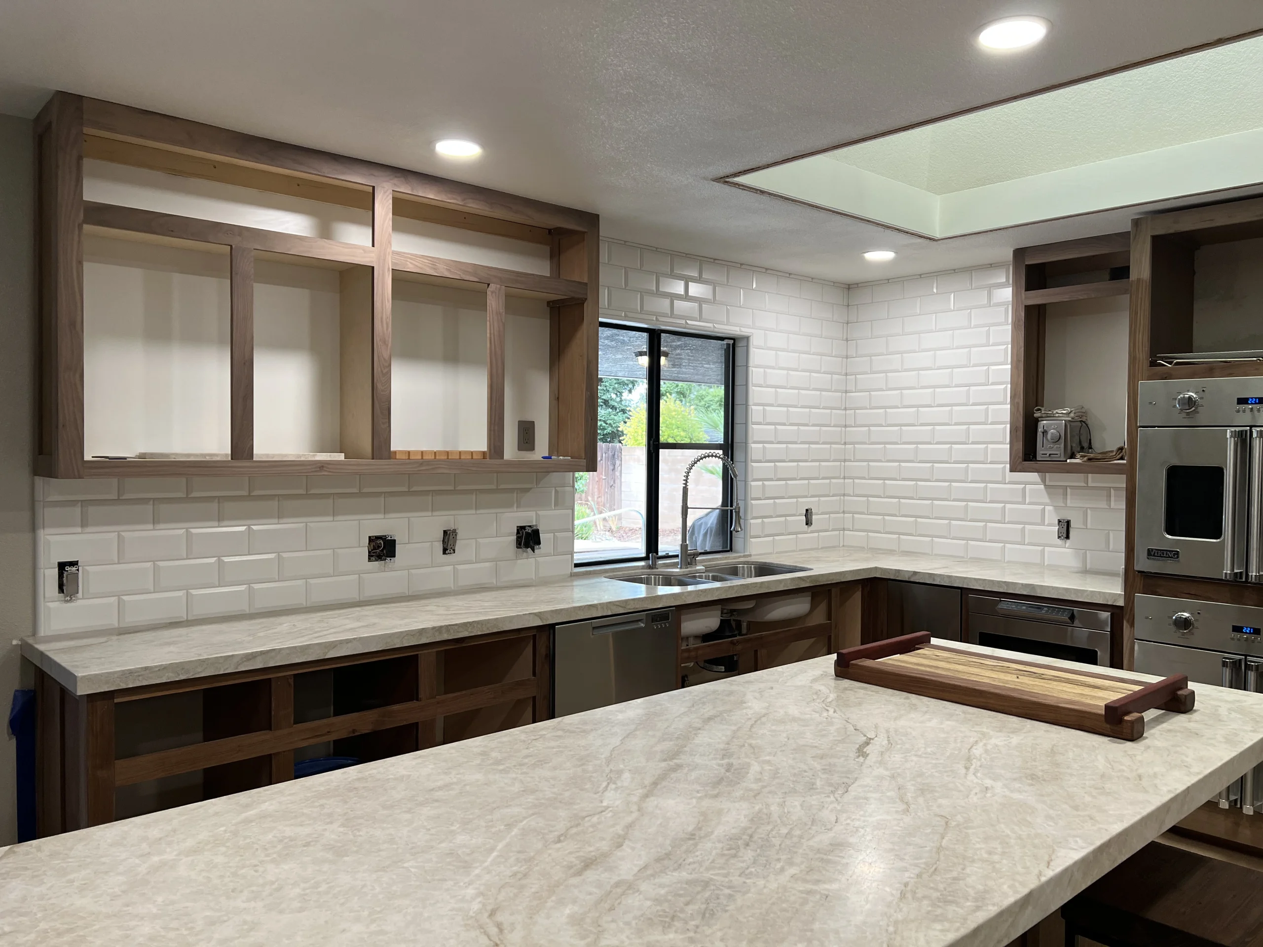 Kitchen remodel in Fresno with white subway tile backsplash, light countertops, and unfinished cabinets.