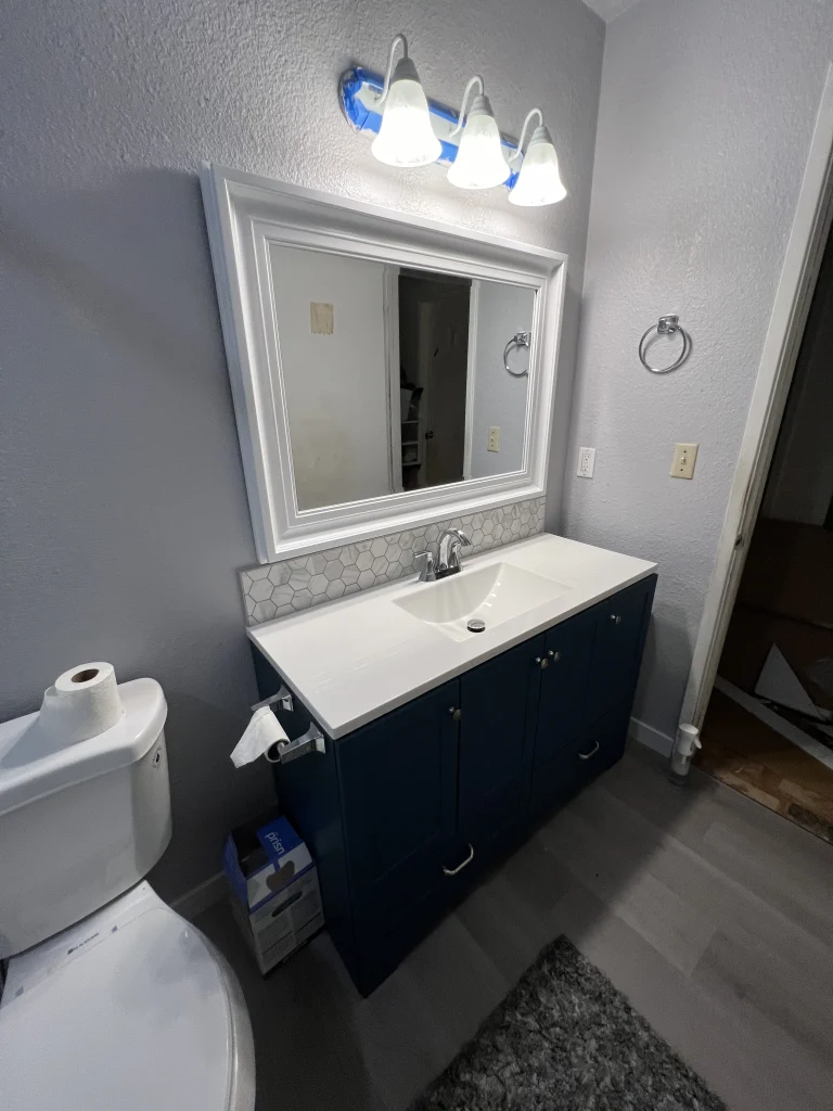 Modern navy blue bathroom vanity with white countertop and hexagon tile backsplash in Fresno, CA.
